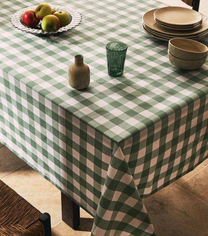 mesa de comedor con mantel resinado a cuadros, bowl con frutas y set de platos