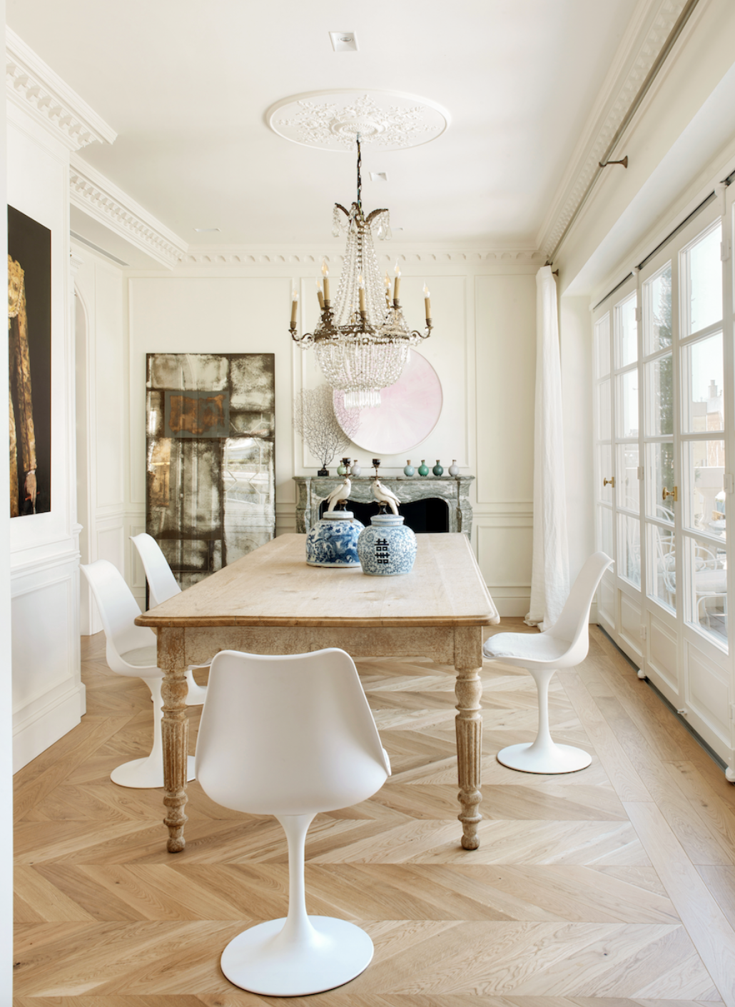 comedor con mesa de madera, lámpara de araña y sillas blancas modernas