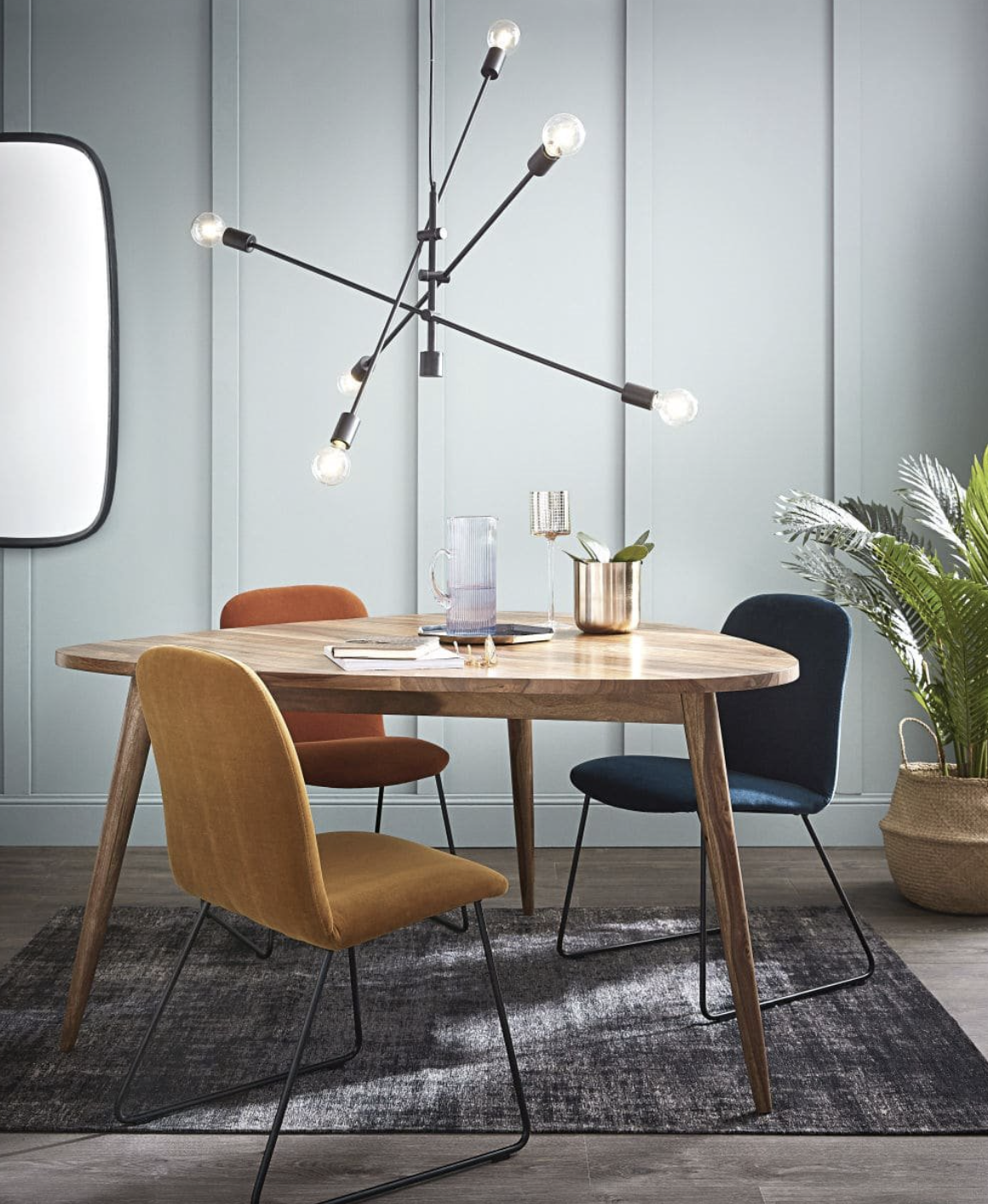 mesa de comedor de madera, lampara de diseño y tres sillas de colores
