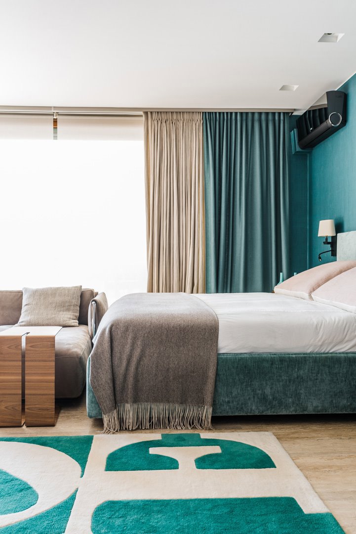 Dormitorio moderno con alfombra, cama, cortinas y pared en azul verdoso
