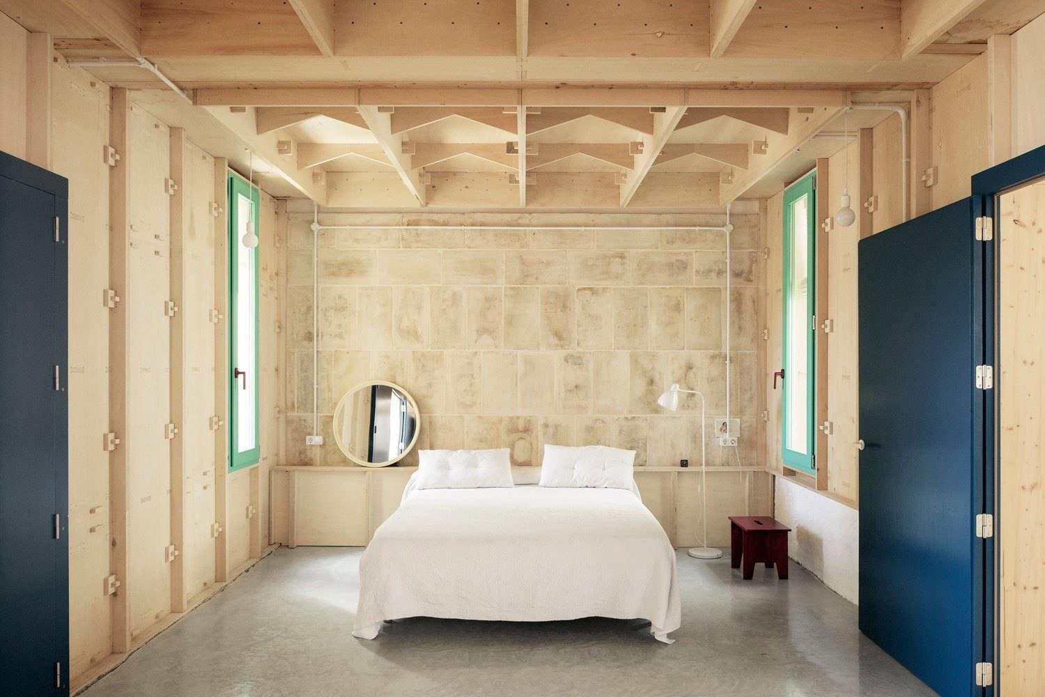 Dormitorio con pared y techo en madera, cama sencilla y puertas en azul