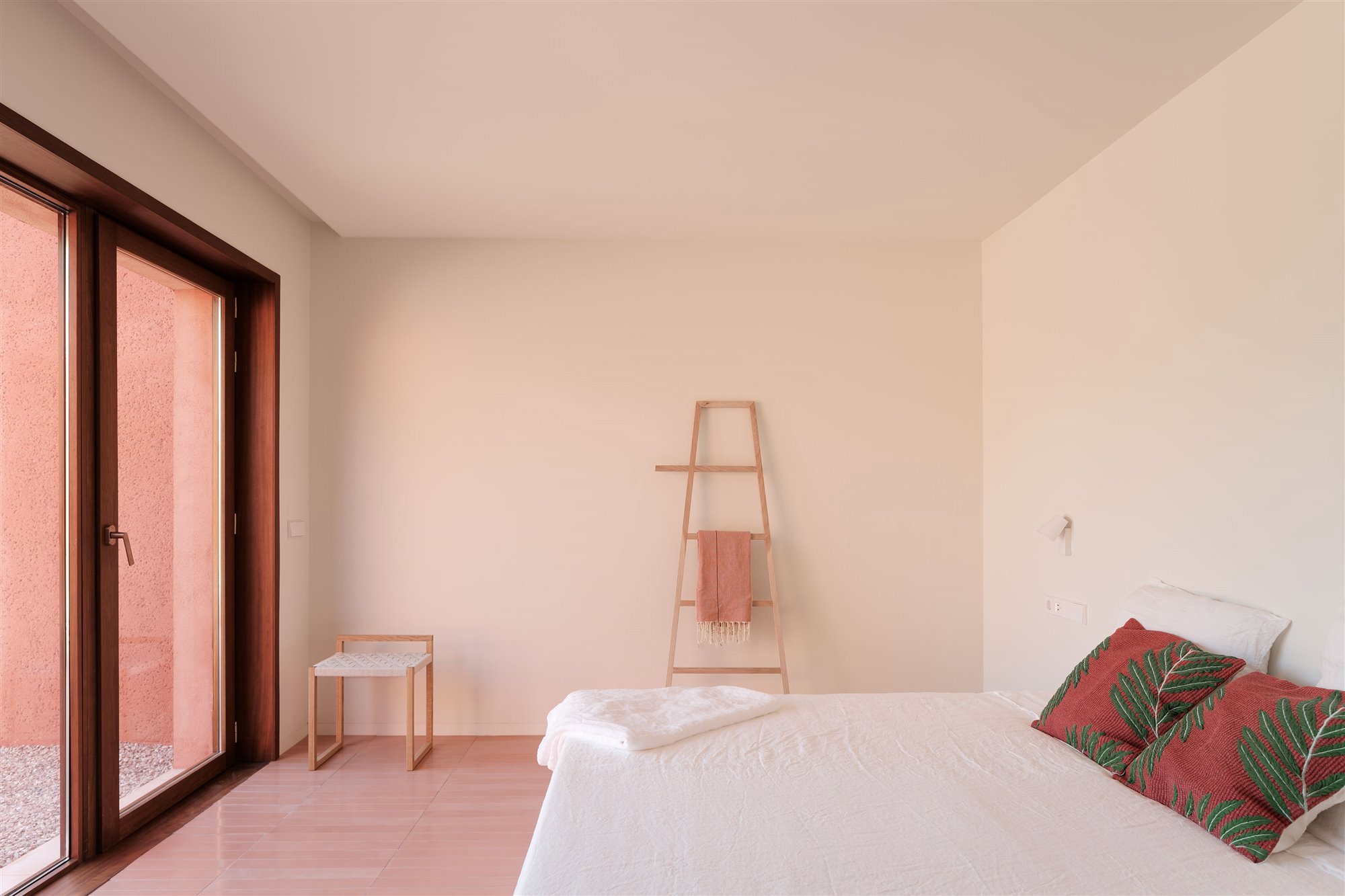 habitación minimalista con cojines en rojo, escalera y taburete