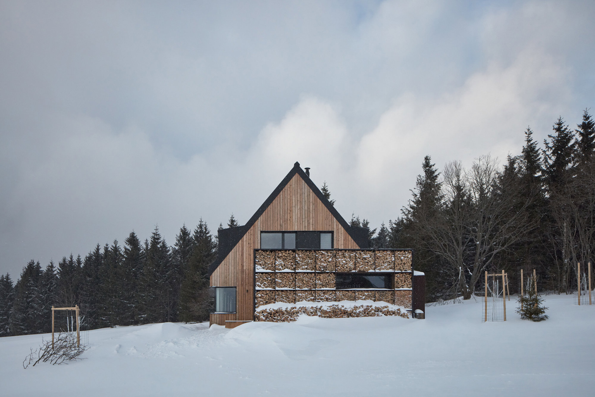 fachada de una cabaña de madera rodeada de nieve en el bosque