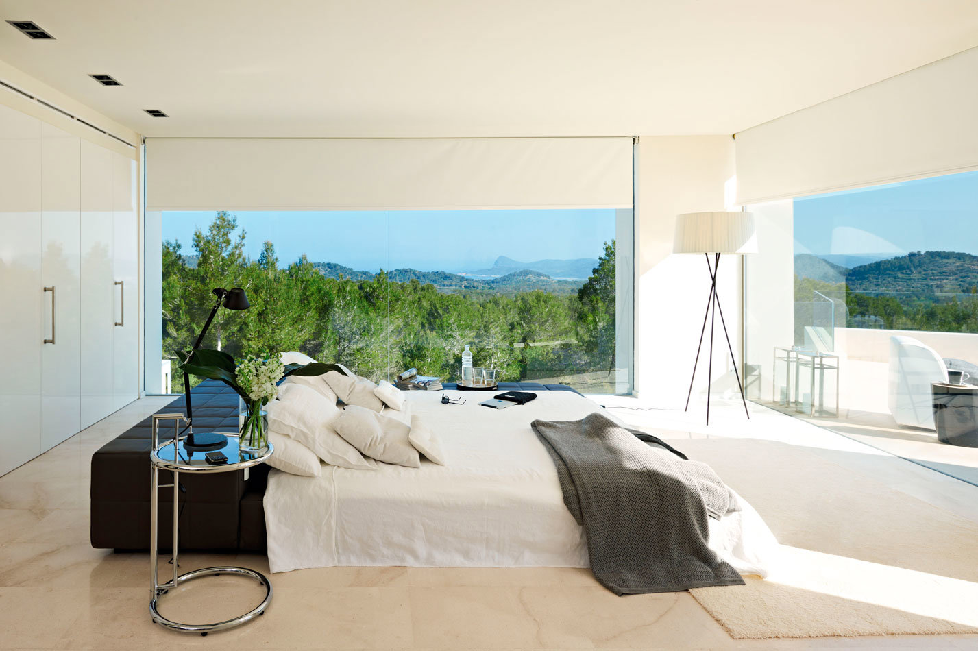 dormitorio con paredes de cristal y vistas a la naturaleza.