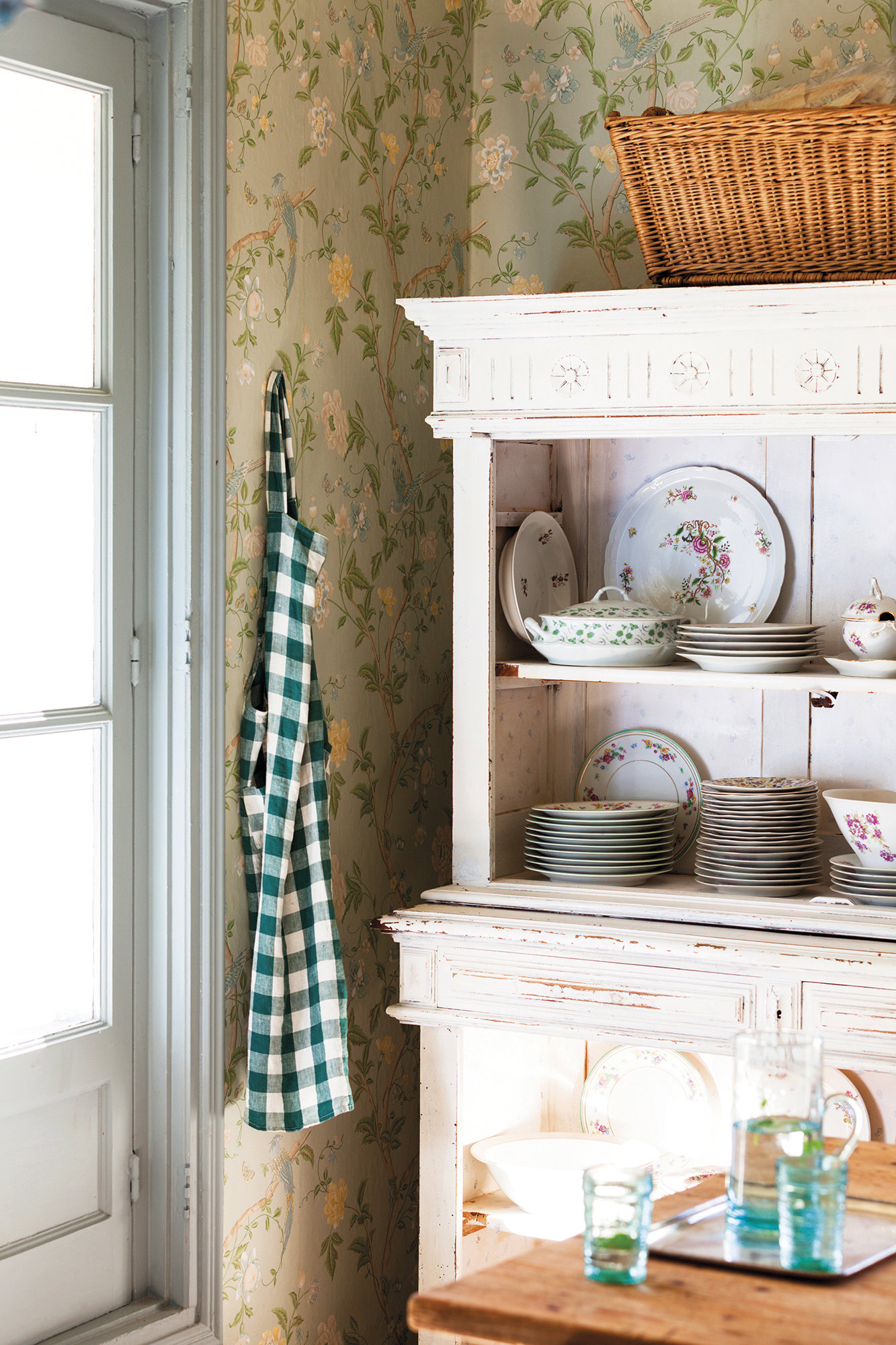 cocina rústica provenzal papel de pared de flores, mueble blanco con vajilla floreada y delantal de cuadros