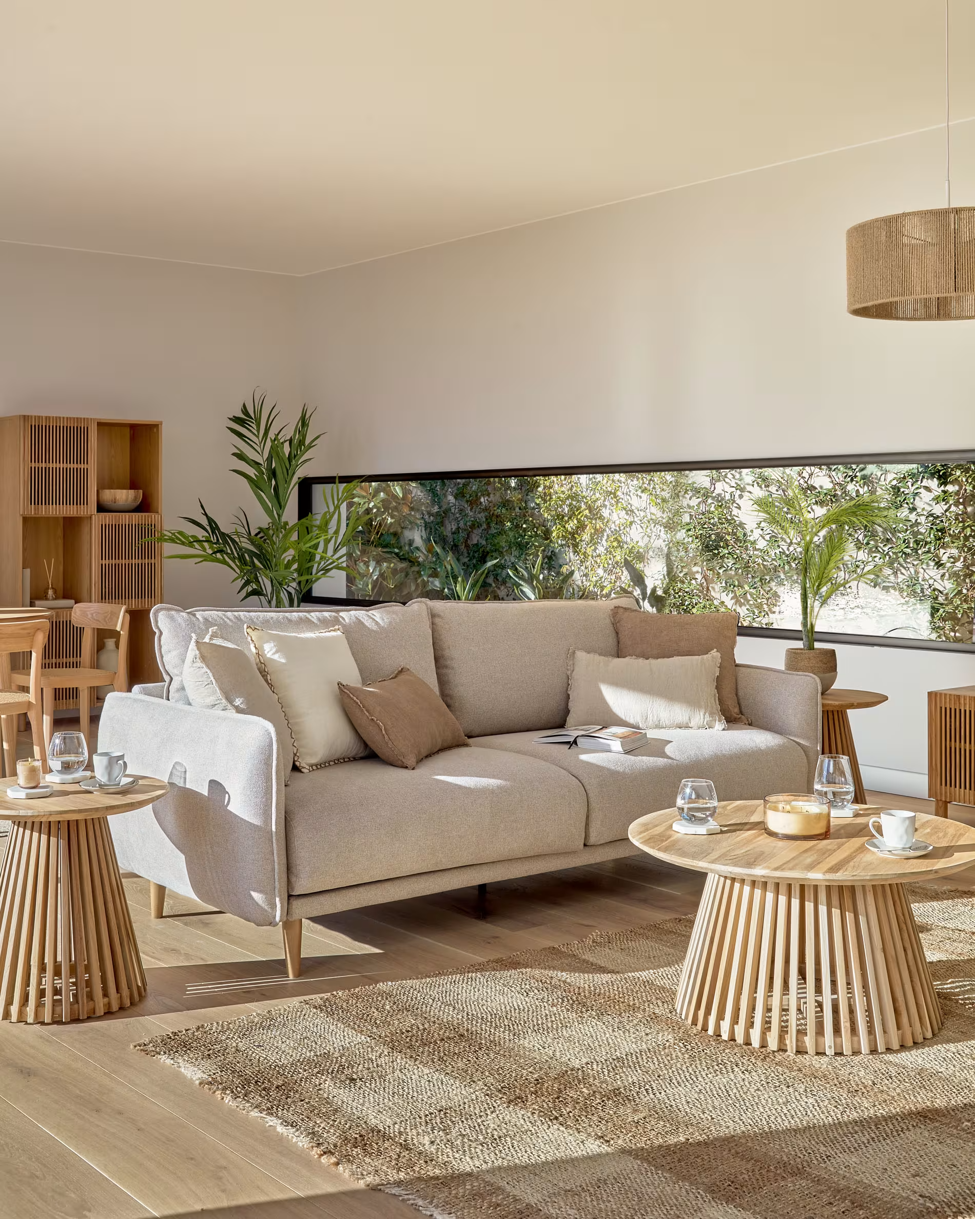 Salón nórdico luminoso con sofá beige y mesa de centro de madera rústica que combina con la alfombra del mismo tono, pero con textura.
