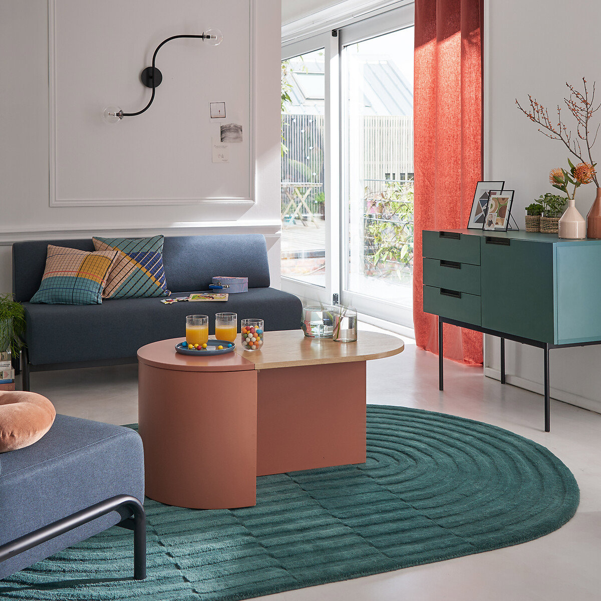 Mesa de centro ovalada con almacenamiento en salón nórdico sobre alfombra de color celeste turquesa. 