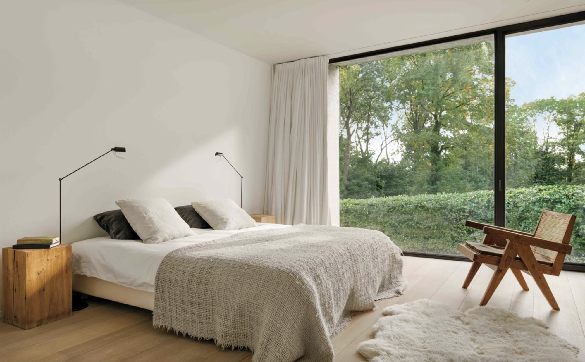 dormitorio con gran ventanal y una butaca de madera
