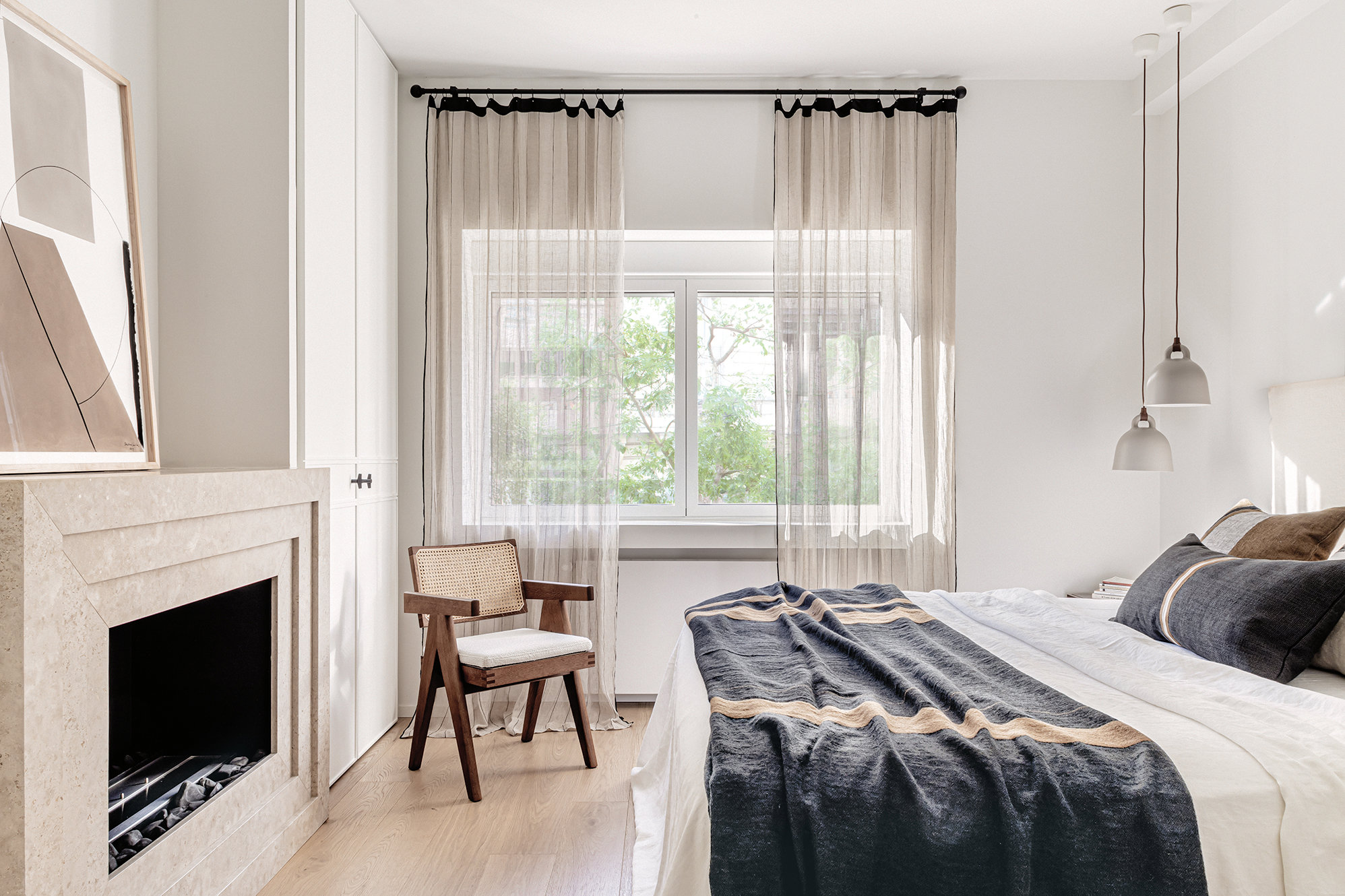 Dormitorio en tonos cálidos con cabecero, cojines y chimenea