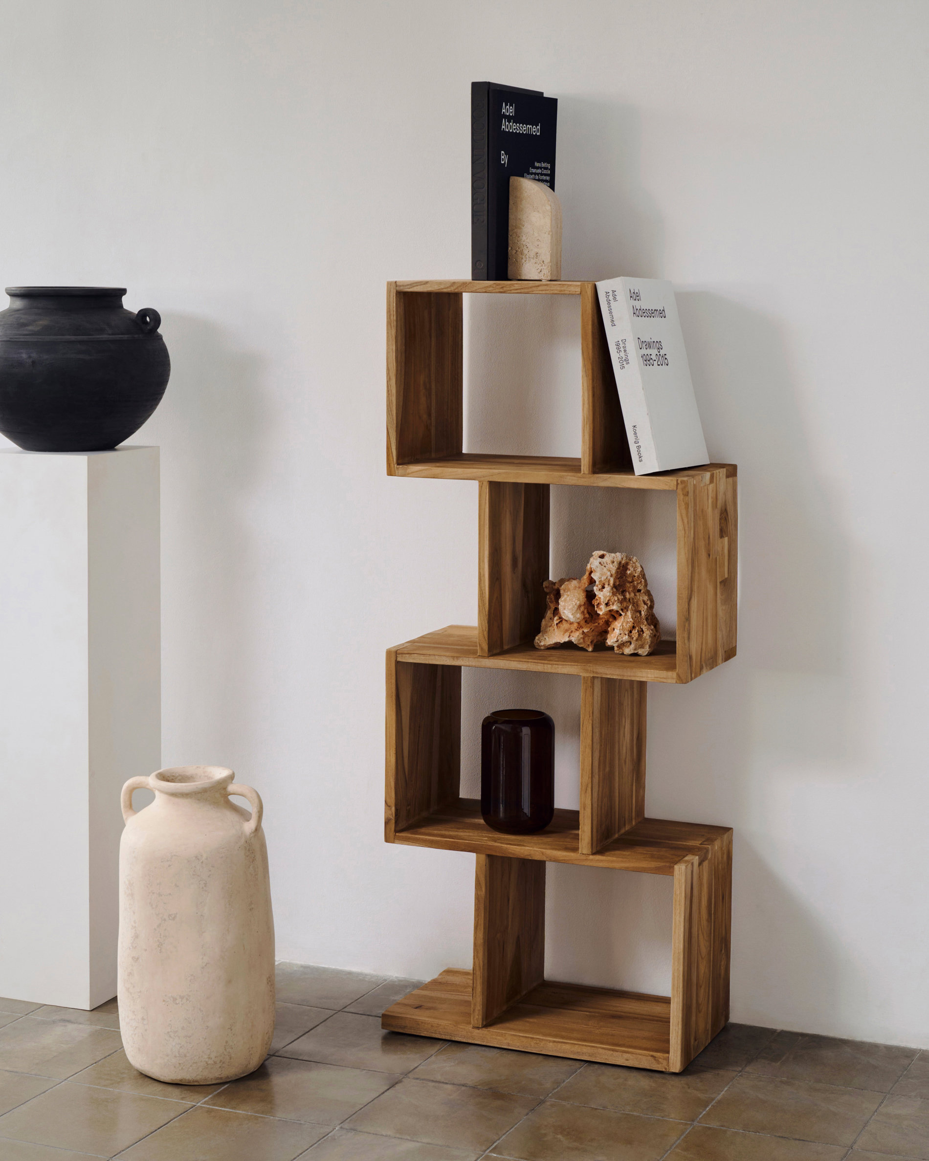 Estantería vertical moderna hecha de cubos de madera decorada con libros y una piedra natural. 