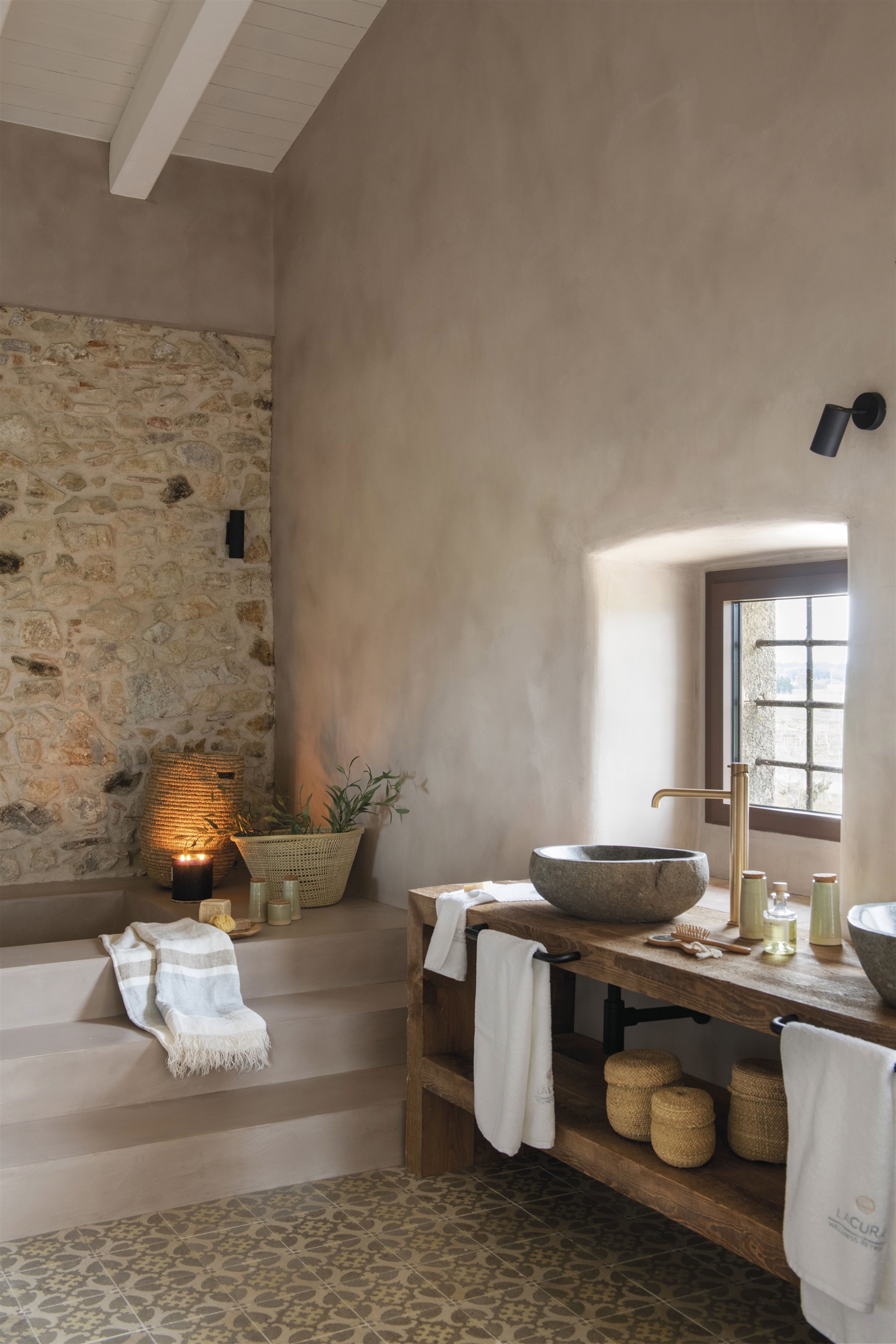 baño rústico pared de piedra, lavamanos redondo, mueble de madera y grifo dorado