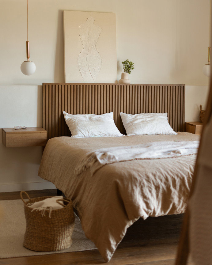 Habitación dormitorio en pared beige respaldo de madera café y un solo cuadro sobre la repisa del respaldo