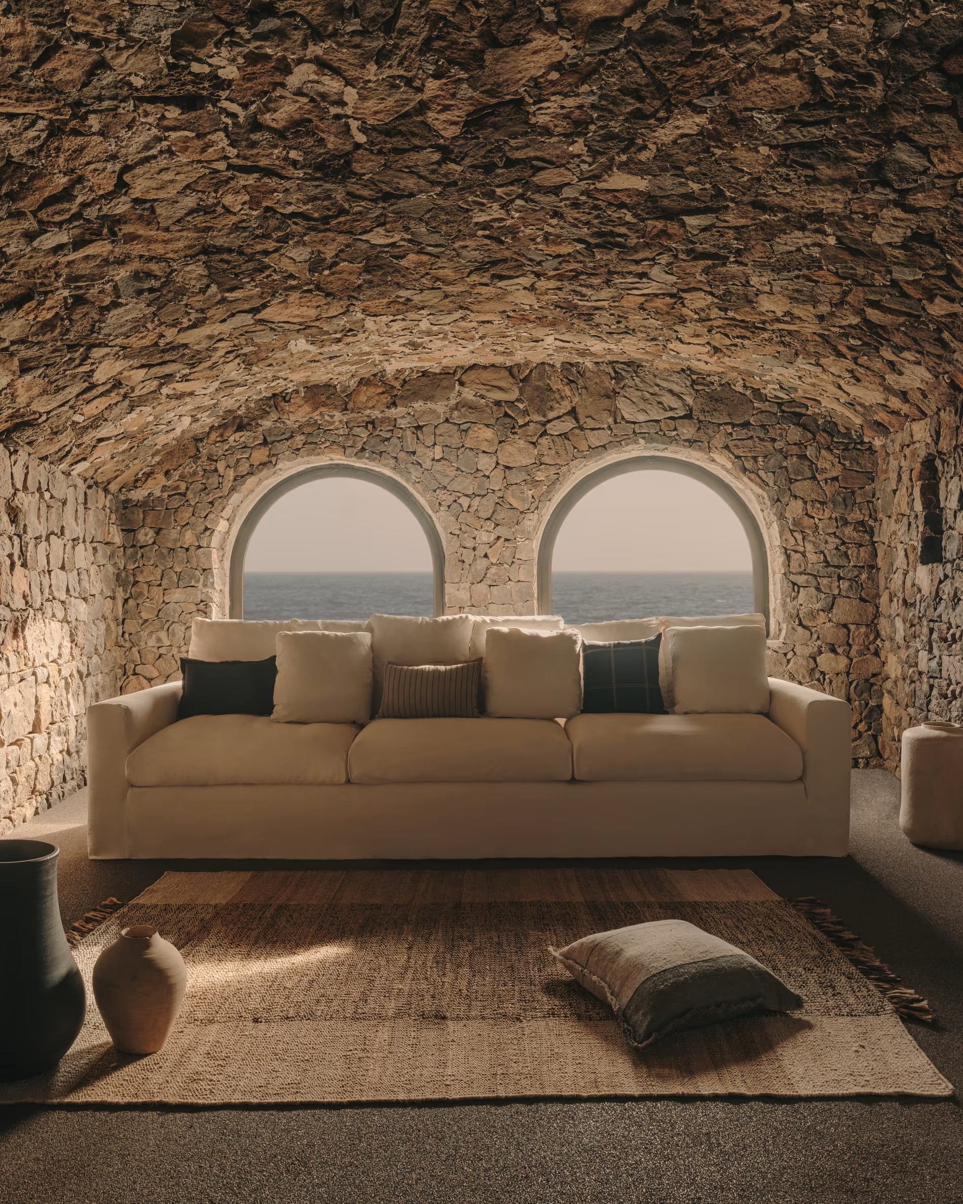 Sofá en salón hecho de piedras rústicas con vistas al mar