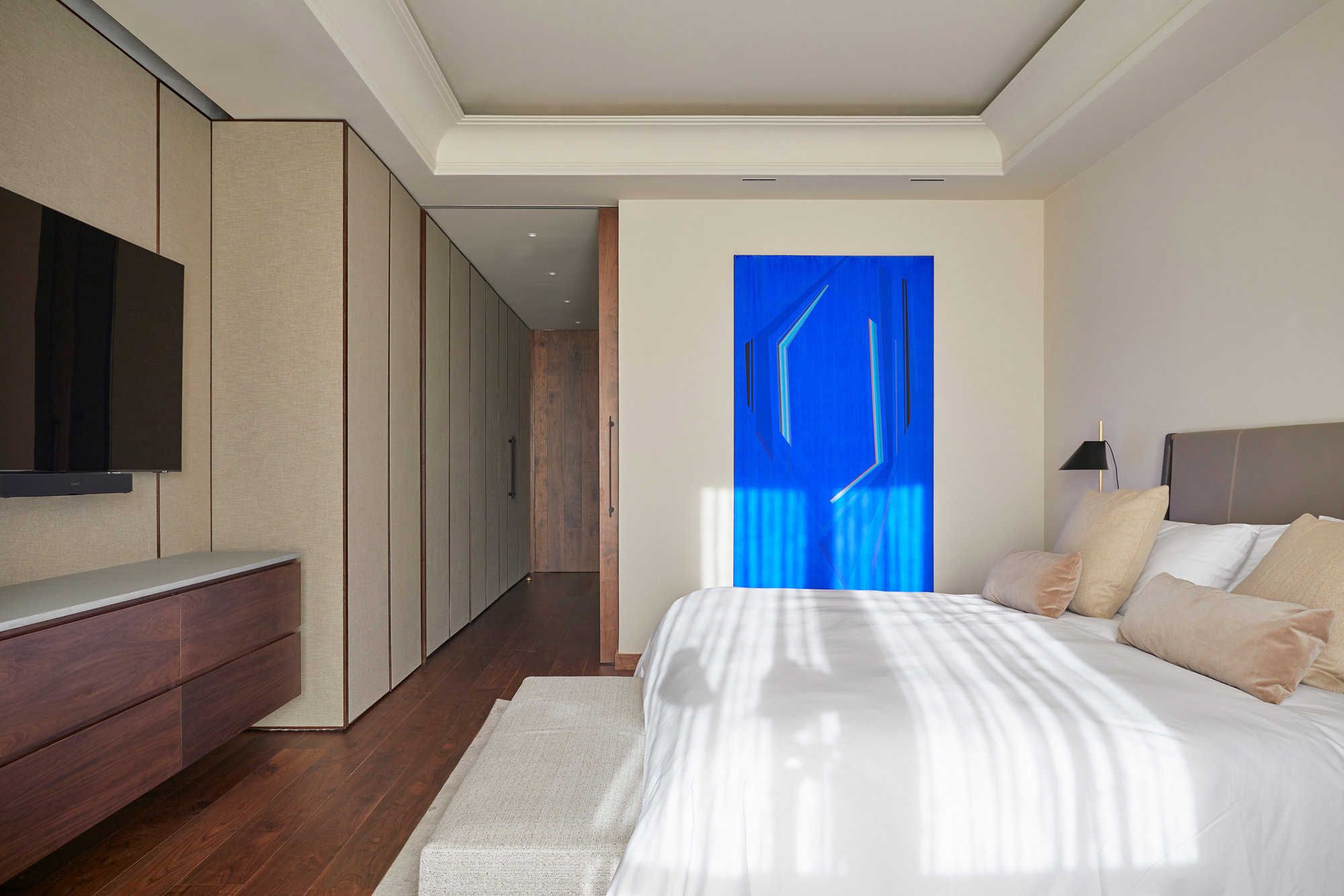 Dormitorio con obra de arte azul y paredes enteladas