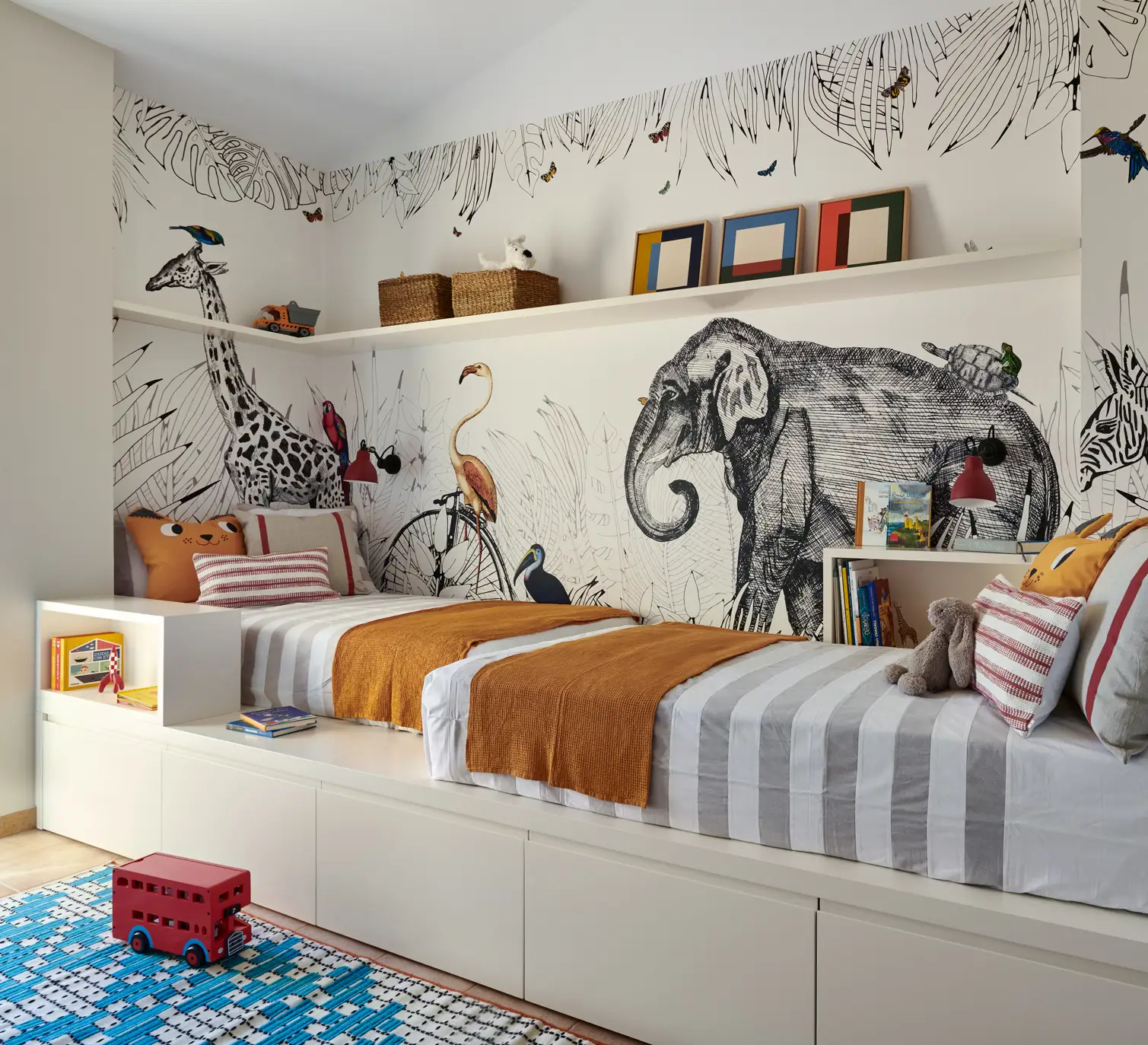 Habitación infantil con papel mural de diseños de animales y cama con canapé en la parte de abajo.