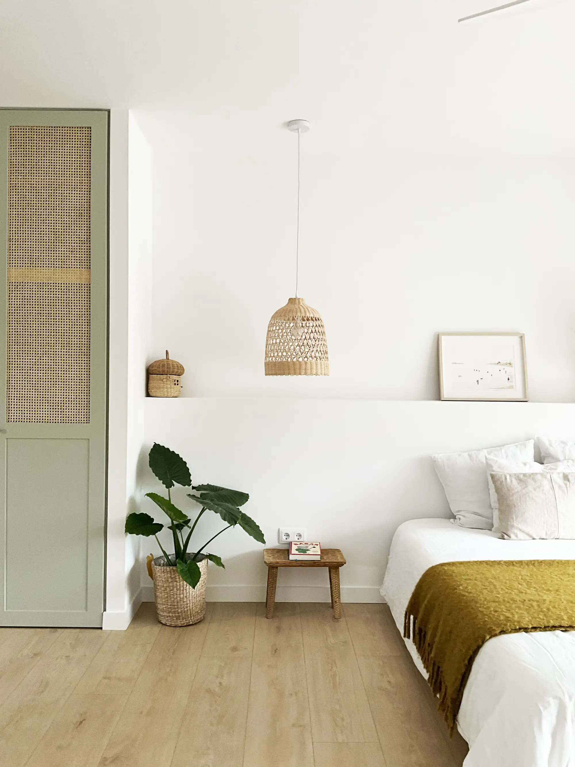 Dormitorio con cabeceros de obra, lámpara colgante y manta color mostaza sobre la cama