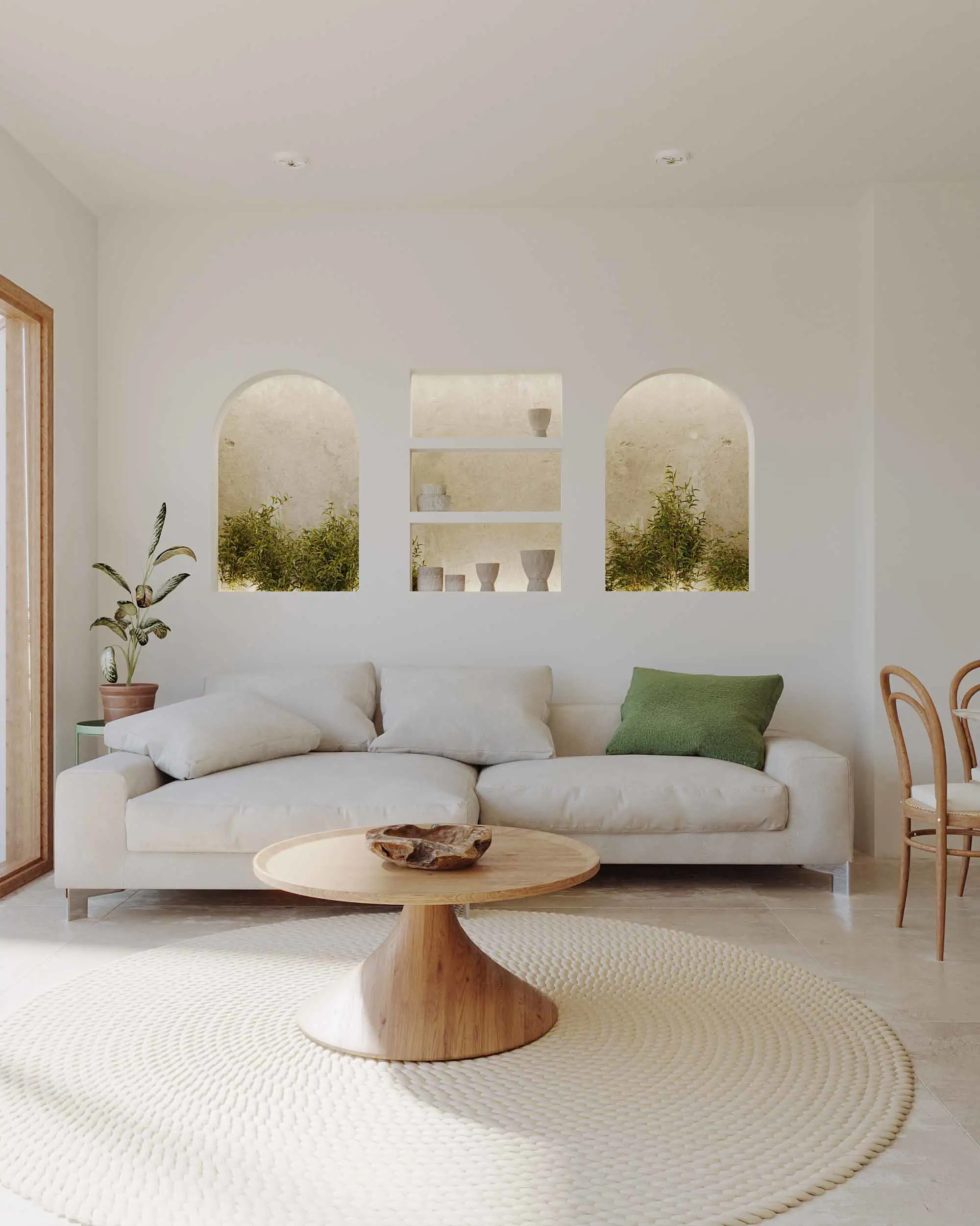 Sofá blanco crudo en salón pintado de blanco con alfombra color marfil y mesita de centro de madera. Sobre el sofá, tres cojines blanco y uno verde musgo. 