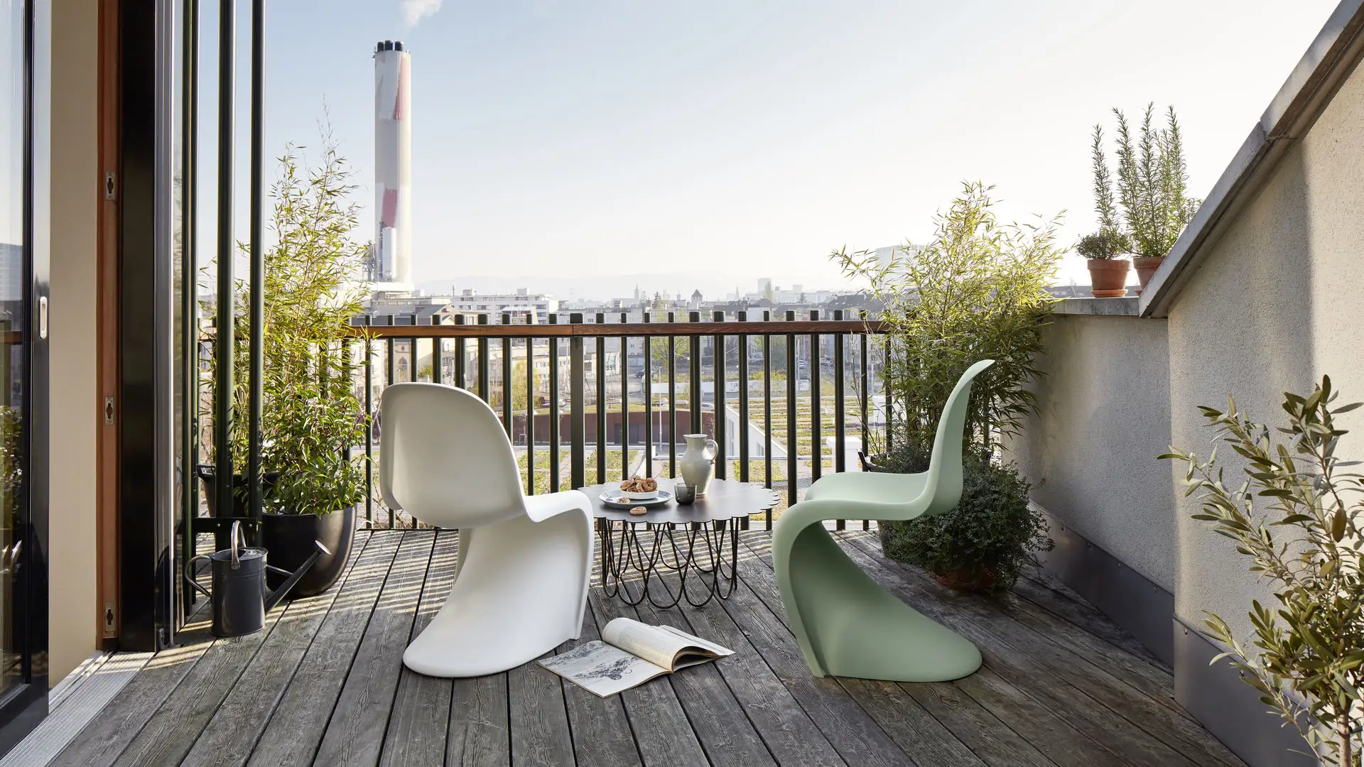 Terraza con suelo de madera, sillas modernas en verde y blanco y al centro la mesa flower table en color negro.