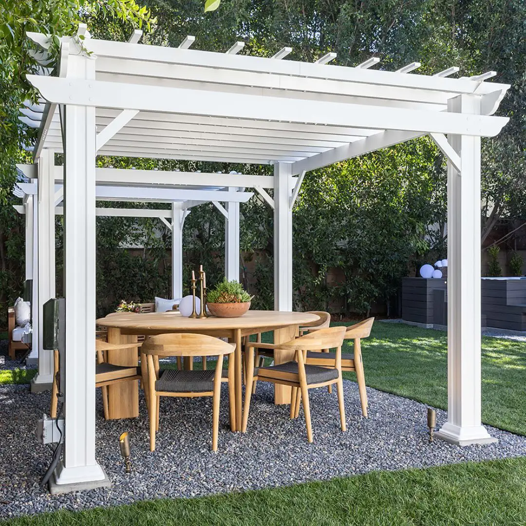 Exterior bajo pérgola de madera blanca con comedor exterior, mesa de madera redonda y sillas con respaldo