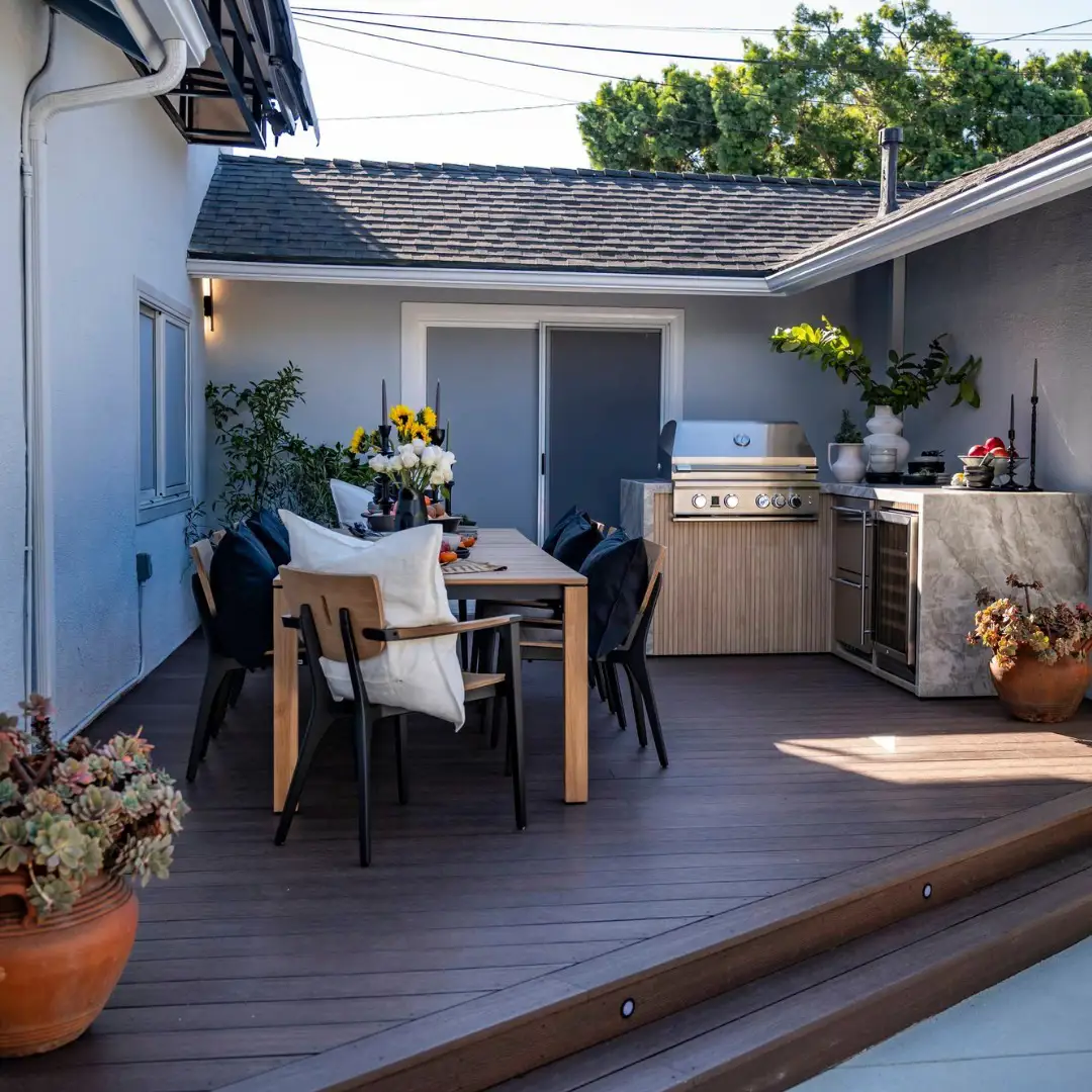 Zona de comedor exterior con cocina exterior en suelo de madera