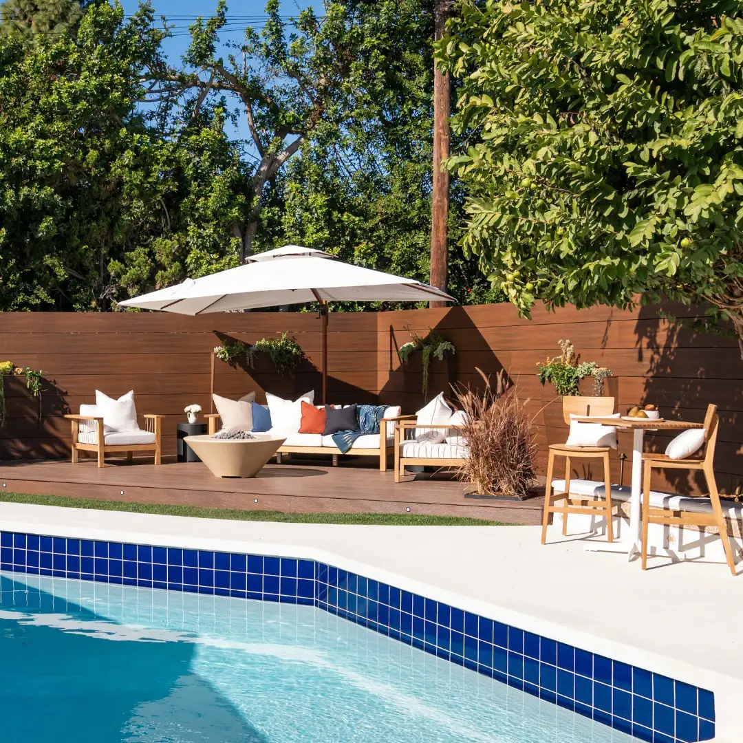 Zona Lounge al lado de la piscina con sofás vestidos de blanco bajo sombrilla blanca