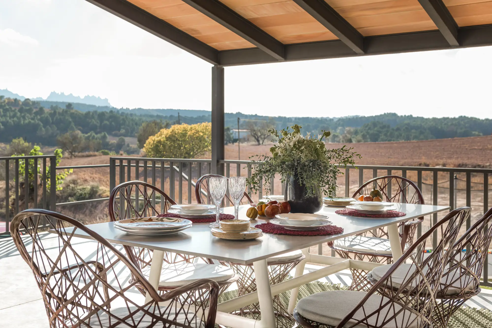 Comedor exterior en proche con mesa amplia y sillas modernas de metal enrejado