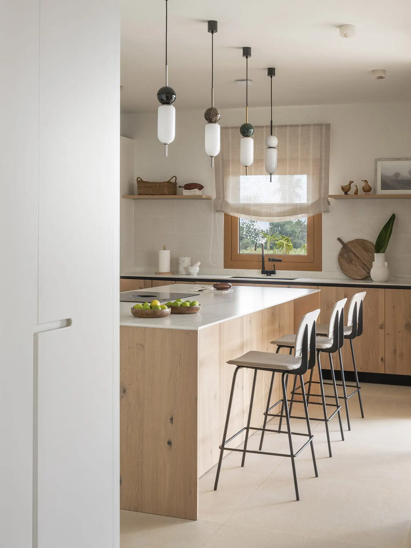 Una cocina de madera con encimera blanca y taburetes blancos. 