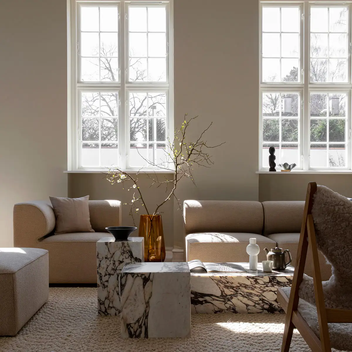 Salón con mesas en forma de cubo de mármol blanco con vetas negras y sofás modulares en color beige