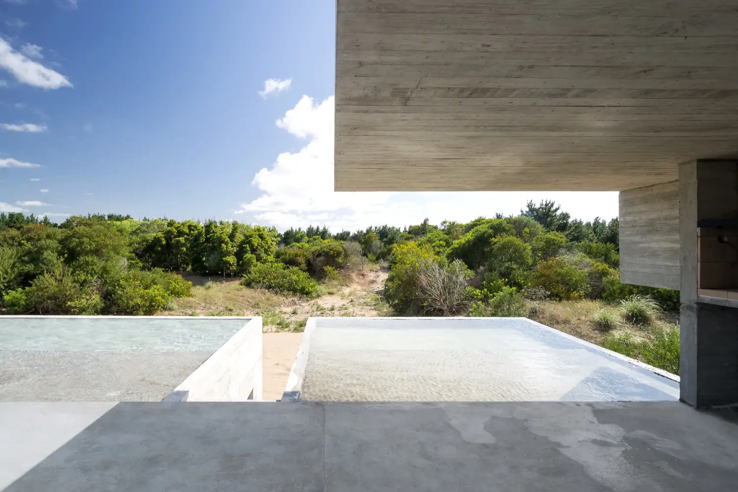 Doble piscina en casa de hormigón construida sobre una duna. 