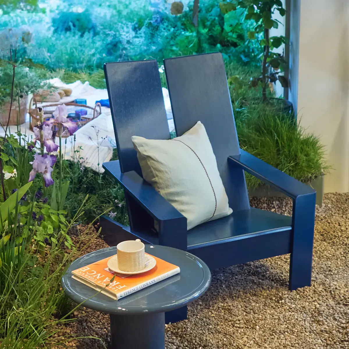 Sillón azul de The Conran Shop acompañado de mesita de café en terraza al aire libre con suelo de piedra.