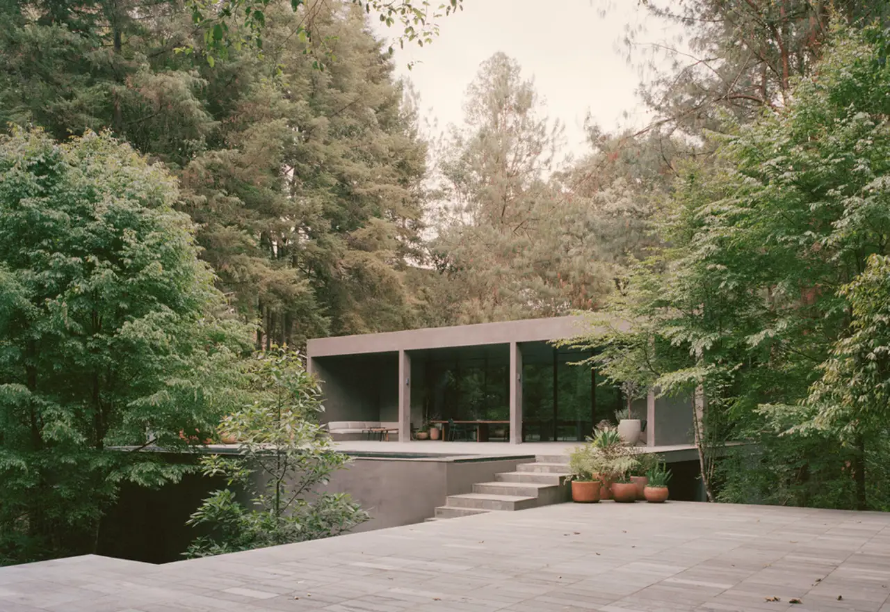 Una enorme roca protagoniza una casa brutalista en México, rodeada de naturaleza y entre las copas de los árboles