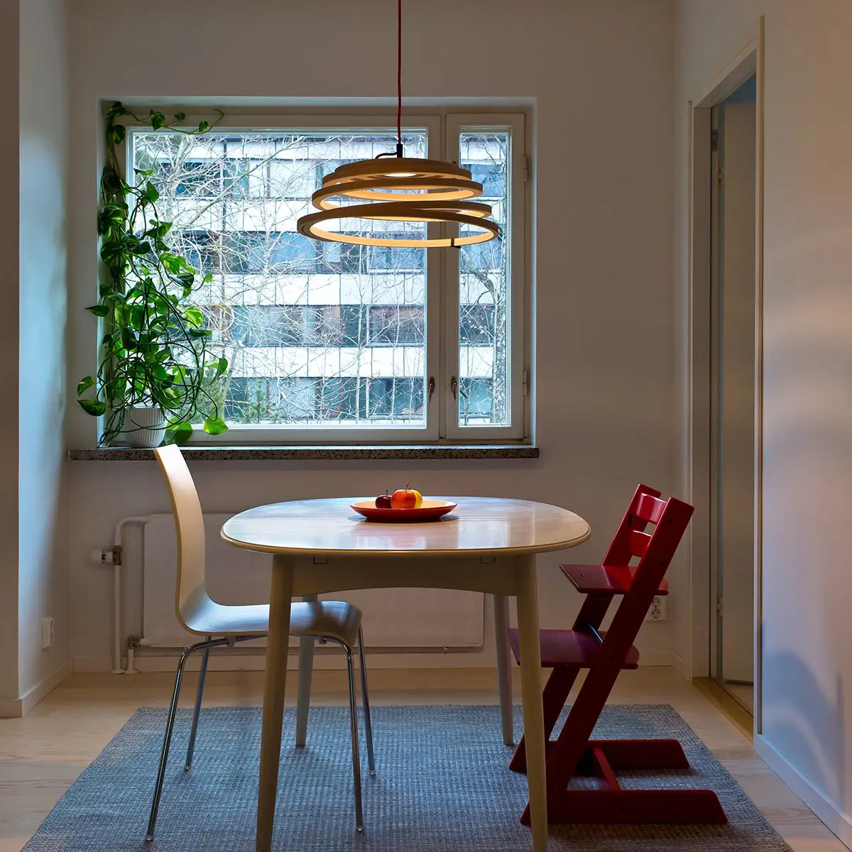 Lámpara colgante en tiras de abedul curvadas y finas sobre mesa de comedor de dos personas.