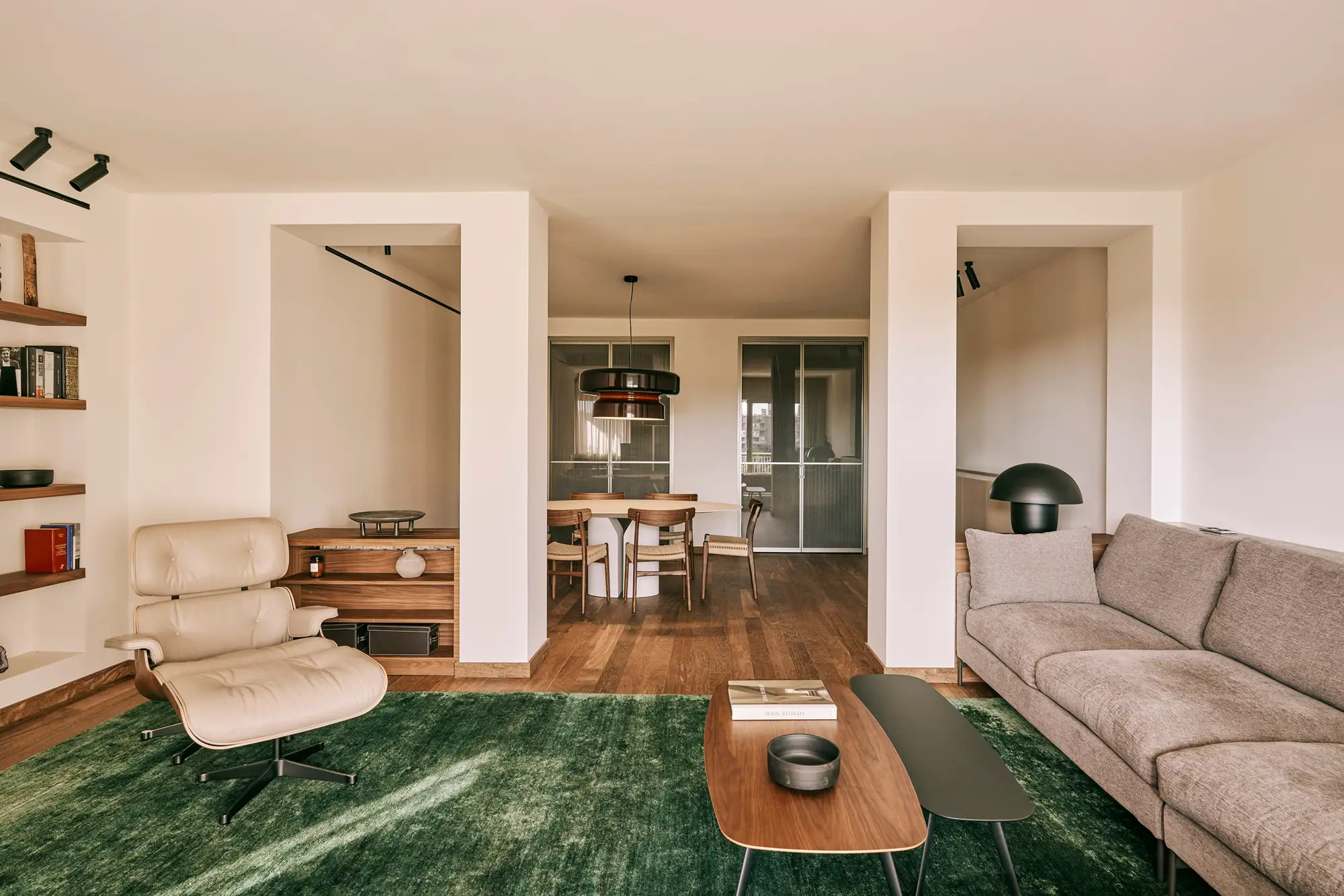 salón verde madera con alfombra en verde oscuro, mesita de centro alargada, sofá gris y butaca. 