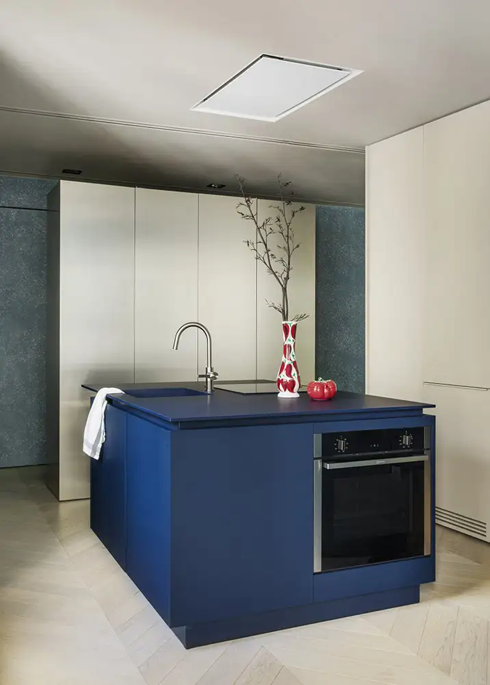 Una isla de cocina en un vibrante azul marino con fregadero y placa, diseño de Febrero Studio.