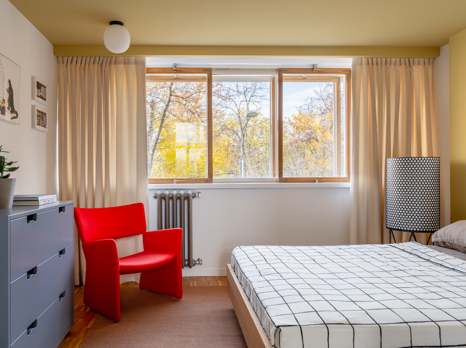 Dormitorio en tonos neutros de estilo mid-century con una butaca roja.