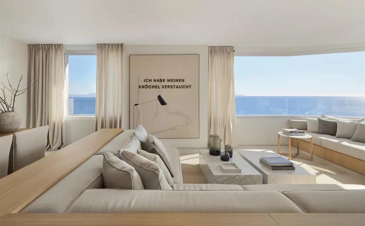 salón minimalista con vistas al mar sofá banco de madera y color blanco roto