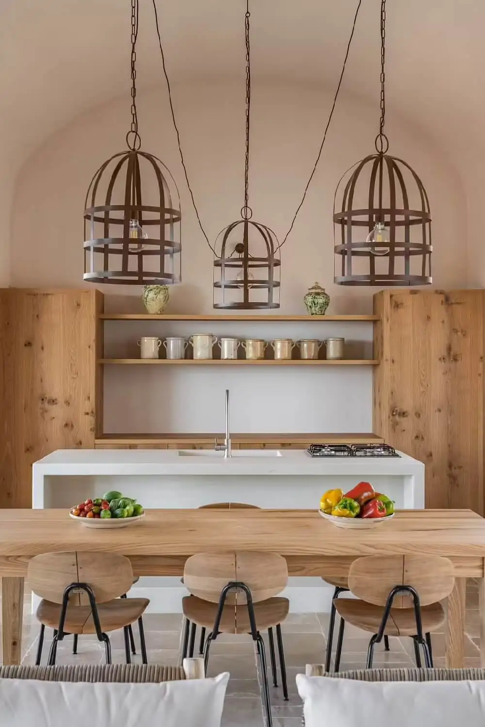 Cocina abierta decorada con tres lámparas tipo jaula en una vivienda en Italia