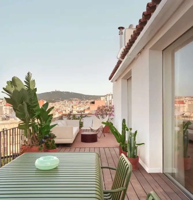 mesa verde con sillas en una terraza blanca