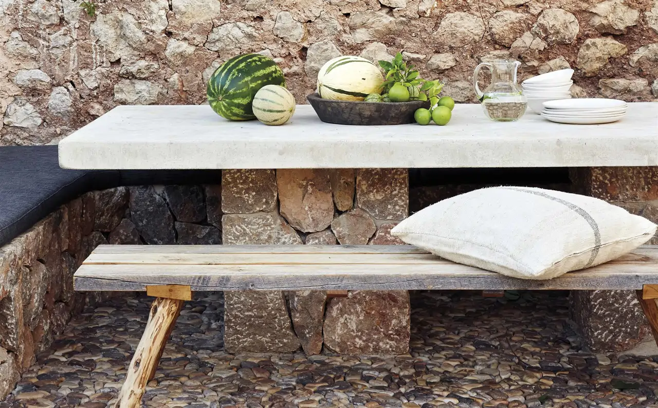 patio de piedra y hiedra con mesa de mármol con frutas y blanco de piedra 