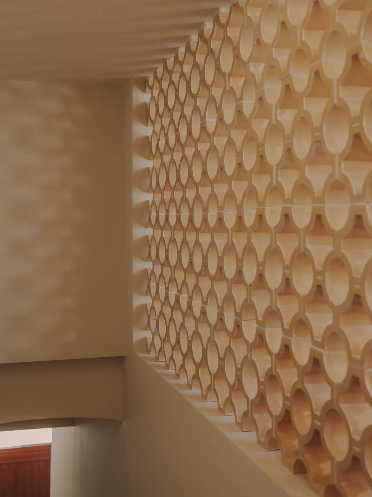 Tras el acceso, esta celosía que deja entrever la zona diáfana de la casa replica de alguna manera las geometrías de los suelos hidráulicos