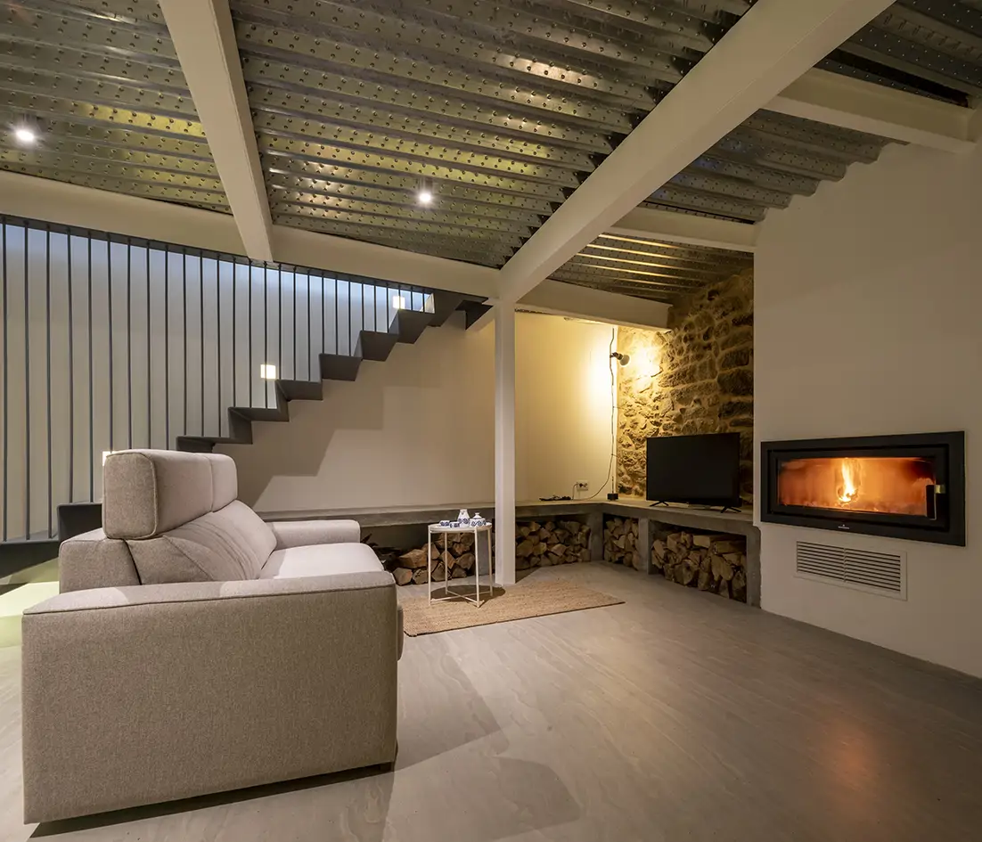 Salón casa rural con muro de piedra y chimenea