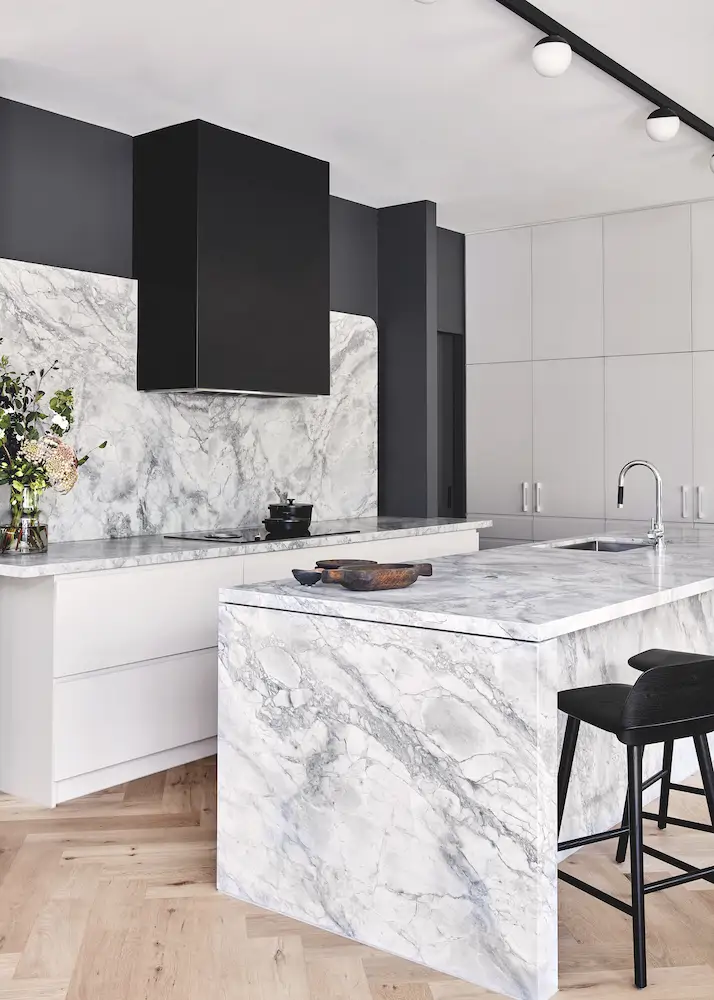 Cocina con taburetes de color negro y encimera de piedra gris