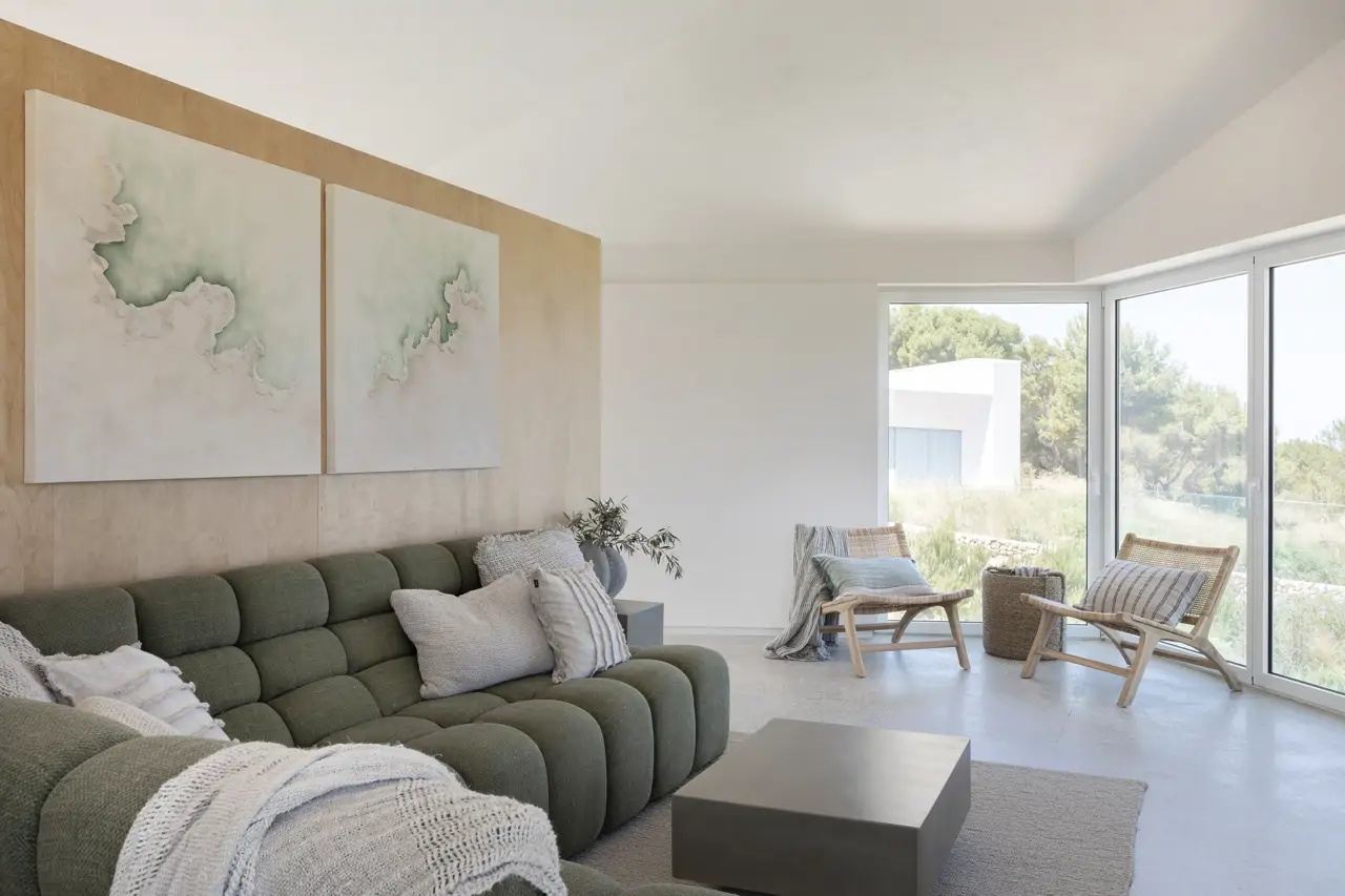 En el salón de esta vivienda en Menorca destaca por su originalidad el sofá verde. El cuadro es de Ana Gómez Jaraíz.