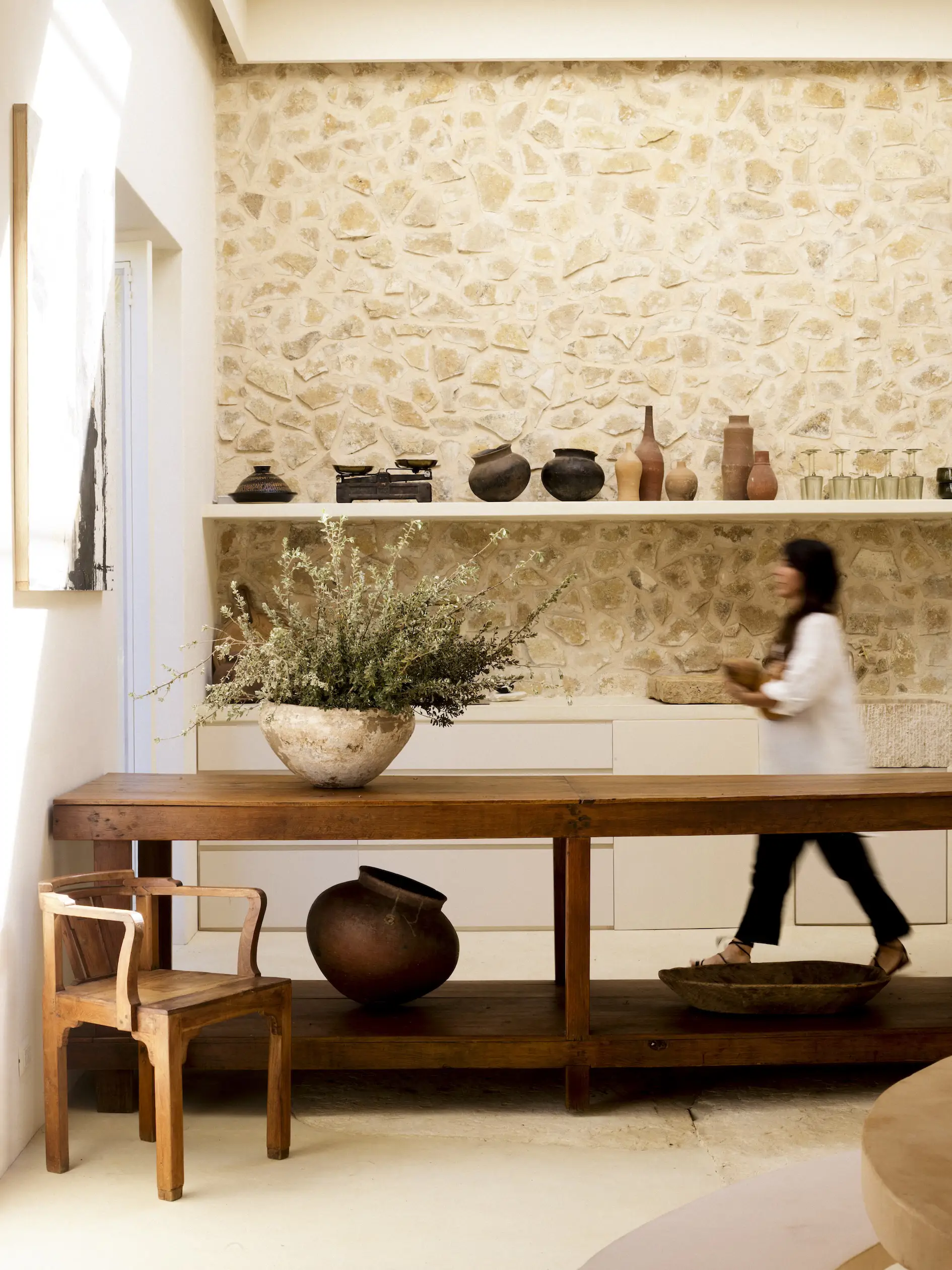 una persona detras de una mesa de madera y pared de piedra al fondo