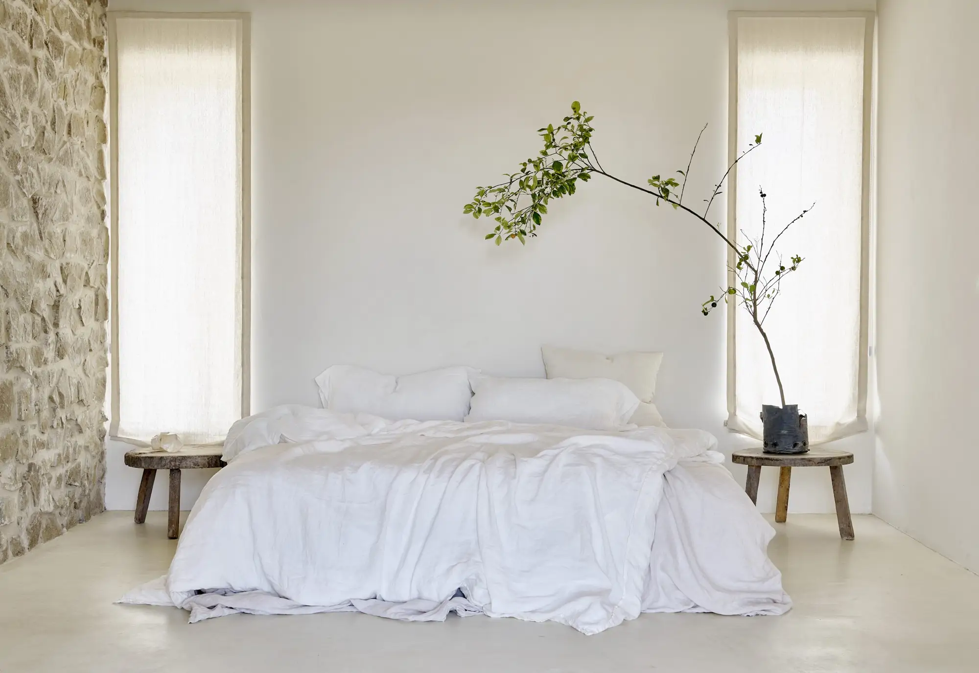 cama con sabanas blancas y una planta grande 