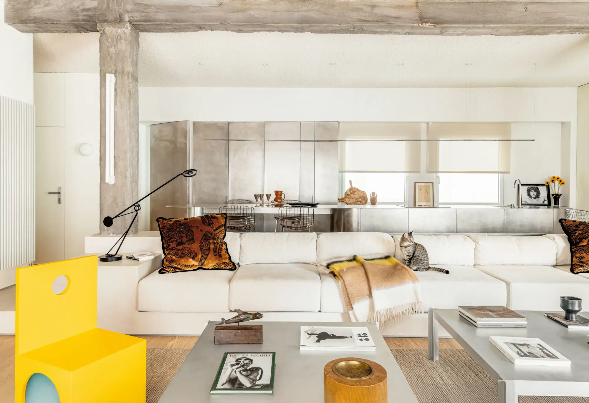 Salón blanco con cocina abierta y silla amarilla