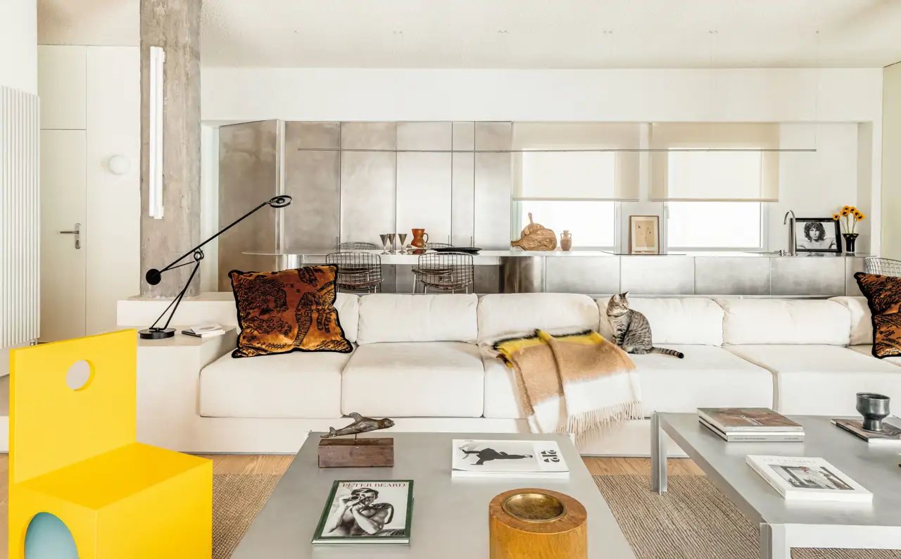 Salón blanco con cocina abierta y silla amarilla