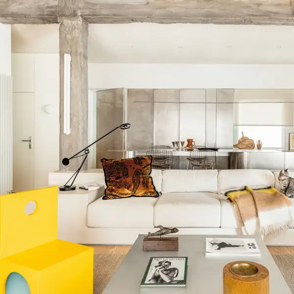 Salón blanco con cocina abierta y silla amarilla