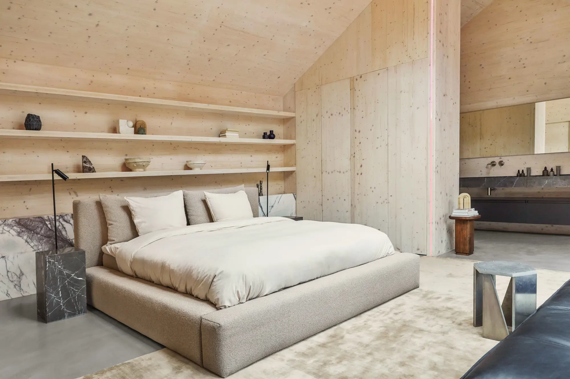Dormitorio con pared del cabecero con estanterías y mesitas de noche de mármol